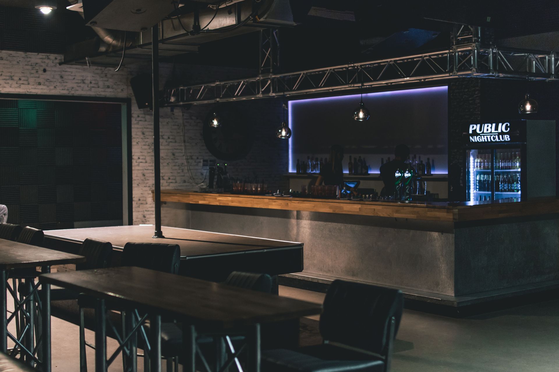 Stylish modern nightclub interior featuring a sleek bar counter with ambient lighting and industrial design elements.